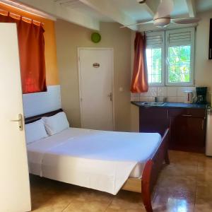 a small bedroom with a white bed and a kitchen at Bungalow de 2 chambres avec piscine partagee jacuzzi et terrasse amenagee a Le Gosier a 5 km de la plage in Le Gosier