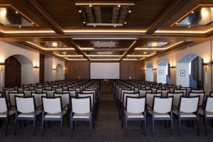 une salle de conférence avec des chaises et un écran blanc dans l'établissement Mont Cervin Palace, à Zermatt