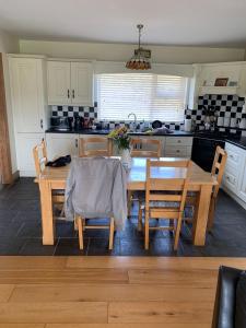 uma cozinha com uma mesa de madeira com cadeiras e uma sala de jantar em Beautiful three bedroom, tranquil home in Ards em Letterkenny