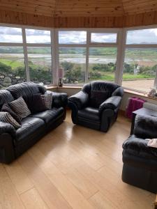 uma sala de estar com duas cadeiras de couro preto e janelas em Beautiful three bedroom, tranquil home in Ards em Letterkenny