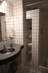 a white tiled bathroom with a sink and a shower at Quiet Haven in the Middle of the City in Budapest