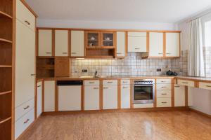 a kitchen with white cabinets and wooden floors at Haus Helena in Mellau