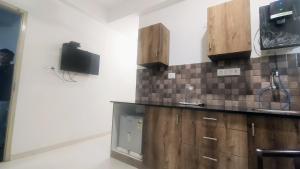 uma cozinha com um lavatório e uma televisão na parede em Brand New Suite Room em Bangalore