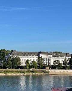 a large white building next to a body of water at Schängelrooms in Koblenz
