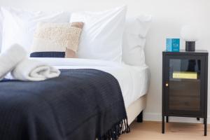 a bed with white sheets and a black night stand at Sweett - Bodeghem in Brussels