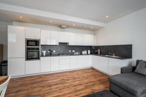 uma cozinha com armários brancos e um sofá em Casa Fresa - Cowgate House em Dundee