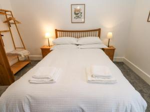 a bedroom with a white bed with towels on it at Bay Tree Cottage in Richmond