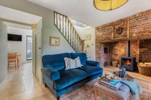 a blue couch in a living room with a fireplace at Little Dorset Cottage in Milton Abbas