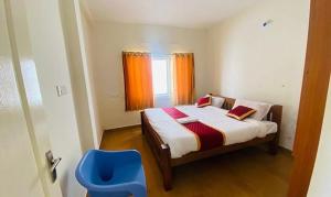 - une petite chambre avec un lit et une chaise bleue dans l'établissement FabHotel Blossom Cottages, à Kodaikānāl