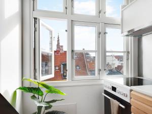 a kitchen with three windows and a potted plant at Sanders Saint - Loft One-Bedroom Apartment By the Charming Canals in Copenhagen
