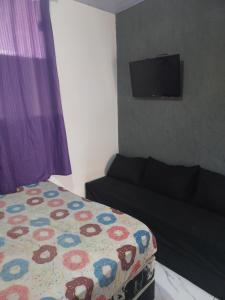 una camera con letto, divano e TV a schermo piatto di Linda Suíte a Cabo Frio