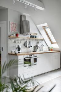 a white kitchen with a sink and a stove at Urokliwy apartament na poddaszu w Gdańsku in Gdańsk