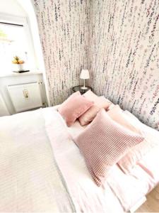 Una cama blanca con almohadas rosas en un dormitorio en Apartament 44, en Lądek-Zdrój