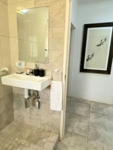 uma casa de banho com um lavatório branco e um espelho. em Endonini House em Nelspruit