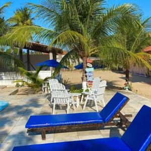 a group of blue chairs and a table and palm trees at Pousada Recanto dos Parente - Icaraizinho de Amontada in Amontada