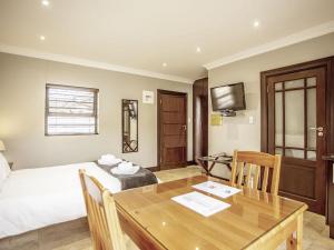 a room with a table and a bed and a television at Two Oceans Stay in Cape Town