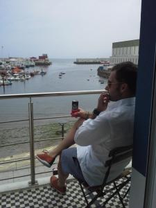 un hombre sentado en una silla tomando una foto del agua en A Casa do Porto, en Burela de Cabo