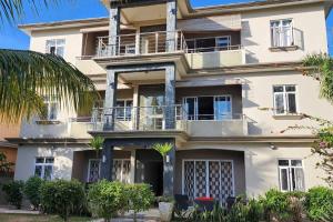 a large white building with balconies and palm trees at Number 8, 2nd Floor, Pebble Bay Apartments in Grand Baie