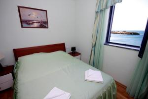 a bedroom with a white bed with a window at Plava Vila Beach Apartments Sveti Stefan in Sveti Stefan