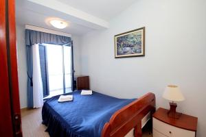 a bedroom with a blue bed and a window at Plava Vila Beach Apartments Sveti Stefan in Sveti Stefan