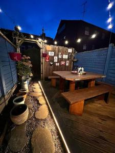un patio de madera con mesa de madera y bancos en Canalside Terrace-Boutique Stay Worcester City, en Worcester