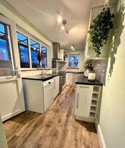 a large kitchen with white cabinets and wooden floors at Canalside Terrace-Boutique Stay Worcester City in Worcester