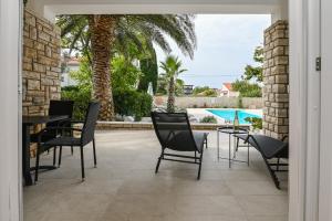 a patio with chairs and a table and a pool at Seagull Pool Apartments & Studios in Novalja