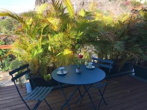 Appartement Artistique de Boucan Canot في Saint-Paul: طاولة وكراسي زرقاء على سطح مع أشجار النخيل