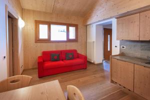 ein Wohnzimmer mit einem roten Sofa und einem Tisch in der Unterkunft La Marmote Albergo Diffuso di Paluzza Ronc in Paluzza