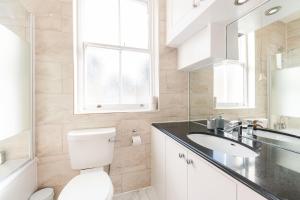 a bathroom with a toilet and a sink and a window at The High Street Kensington Boutique in London