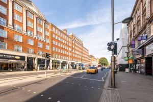 ロンドンにあるThe High Street Kensington Boutiqueの黄色い車が建物のある街路を走る