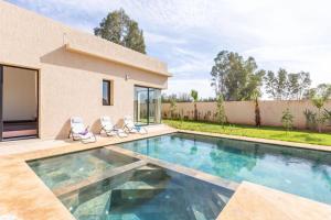 a swimming pool with two chairs and a house at Luxury stylish 3suits villa in Marrakesh