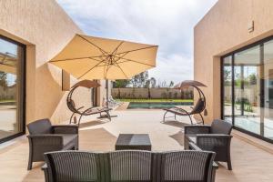 une terrasse avec une table, des chaises et un parasol dans l'établissement Luxury stylish 3suits villa, à Marrakech