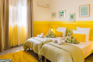 two beds in a hotel room with yellow walls at Kaz Zevi in Saint-Paul