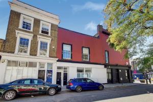 two cars parked in front of a red and white building at Luxurious 4 Bedroom Entire Flat in King's Cross in London