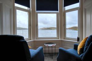 a room with two chairs and windows looking out at the water at MacKays in Oban