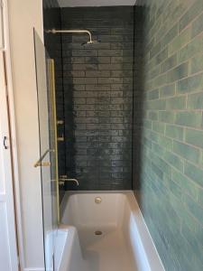 a bathroom with a white tub and a brick wall at Townhouse Apartment in Oswestry