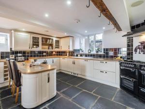 a large kitchen with white cabinets and black appliances at Greenbank Farm House in Cartmel