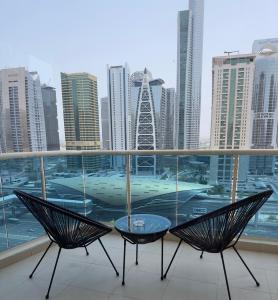 smilehomesdxb في دبي: بلكونه فيها كرسيين وطاولة ومدينة