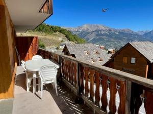 a balcony with a table and chairs and mountains at Appartement Pra-Loup, 3 pièces, 8 personnes - FR-1-165A-45 in Uvernet
