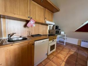 a kitchen with wooden cabinets and a sink at T2 mezzanine à Pra-Loup 1500, proche navette et vue montagnes - FR-1-165A-59 in Uvernet-Fours +9 photos