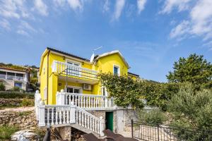 a yellow house with a white fence in front of it at Seaview House Helena Apartments - Happy Rentals in Plomin