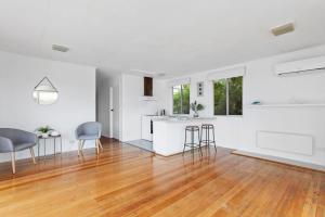 een lege woonkamer met witte muren en houten vloeren bij Great Ocean Road Sandy Villa in Apollo Bay +20 foto's