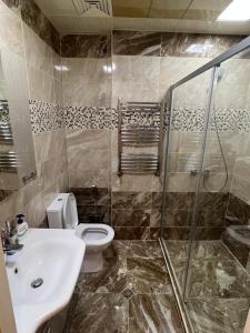 a bathroom with a toilet and a sink and a shower at Cozy & Spacious Apartment in Baku