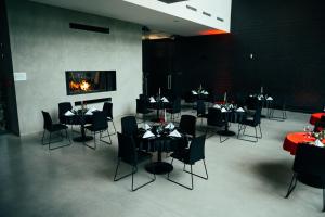 a restaurant with black tables and chairs and a fireplace at Hotel Skansen Conference&Spa in Studzieniec
