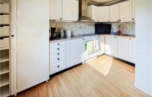 uma cozinha com armários brancos e piso em madeira em Amazing Home In Ljungby With Harbor View em Ljungby