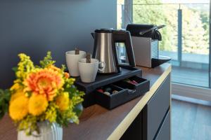 a counter with a coffee maker and a vase of flowers at Hotel am Schwanenhaus in Dresden
