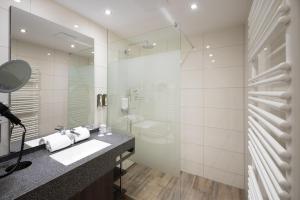a bathroom with a sink and a toilet and a mirror at Concorde Hotel am Leineschloss in Hannover +48 photos
