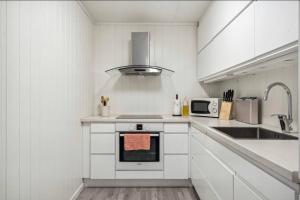 a white kitchen with a stove and a sink at Rolig og avslappende in Tromsø