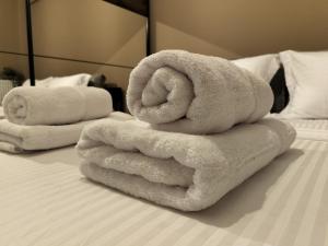 une pile de serviettes assises au-dessus d'un lit dans l'établissement PanoramicView180 1BR Welcome Stay Lux Penthouse Apartment, à Thessalonique